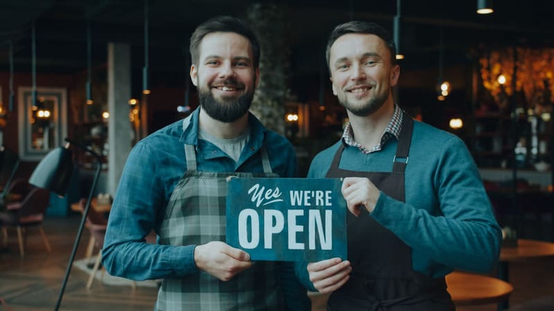 Socios de un restaurante con el cartel de abierto